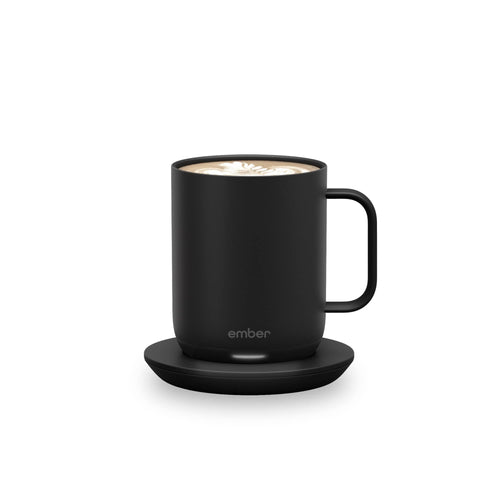  A matte black Ember Smart Mug 2 with a glowing white LED indicator at the base, sitting on a neutral grey surface. Features the Bold Leadership Path logo.